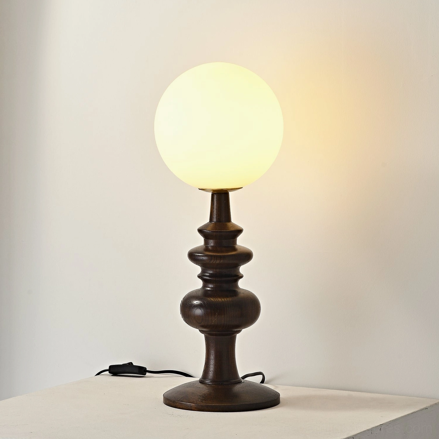 Elegant Sveta table lamp - turned dark wood base with frosted globe shade emitting soft ambient illumination