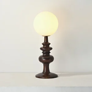 Modern Sveta table lamp lit with warm ambient glow - walnut wood turned base with illuminated frosted glass globe