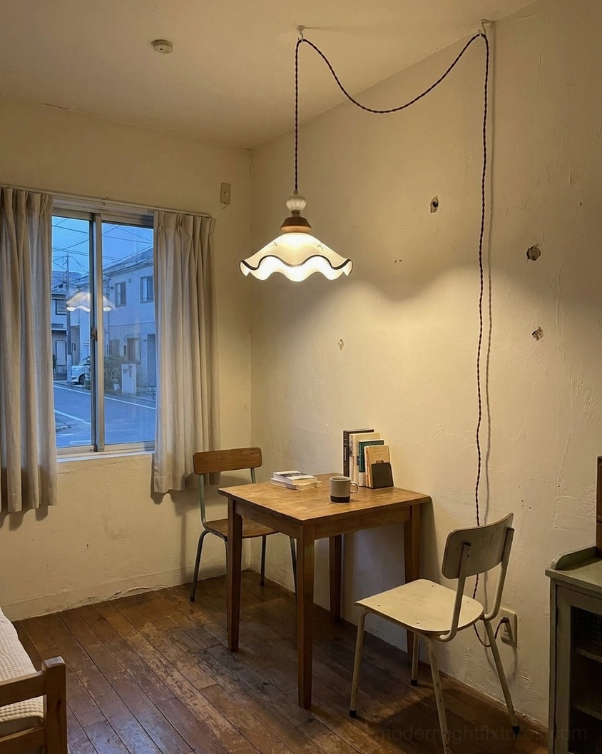 Plug-in pendant light with braided cord draped in cottage dining area with wood plank floor and natural window light