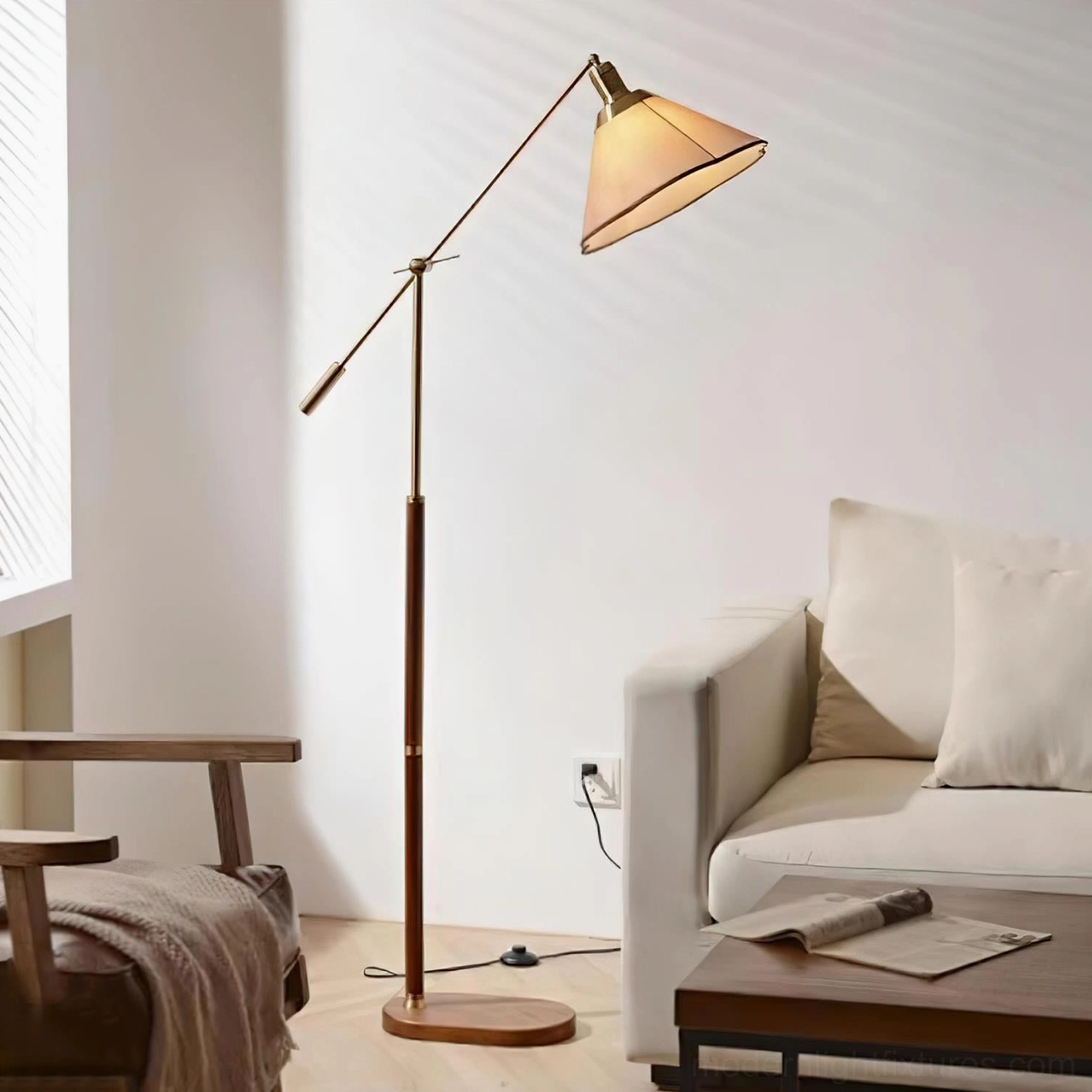 Illuminated swing arm floor lamp with gold finish metal arm, walnut wood pole, and warm glowing fabric shade in relaxed living room