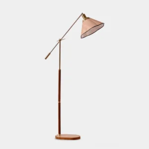 Modern adjustable swing arm floor lamp with walnut wood pole, brass metal accents, and fabric shade in contemporary living room setting