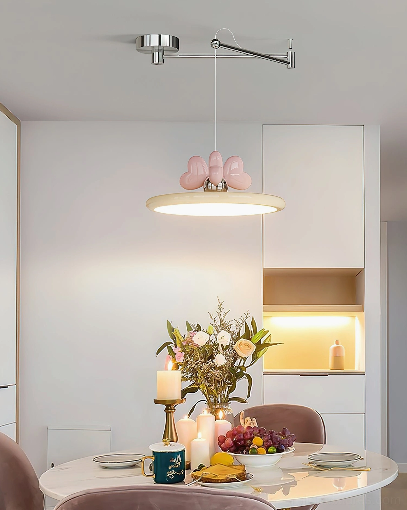 Dining room pendant light fixture above round table with warm ambient lighting and floral table decor