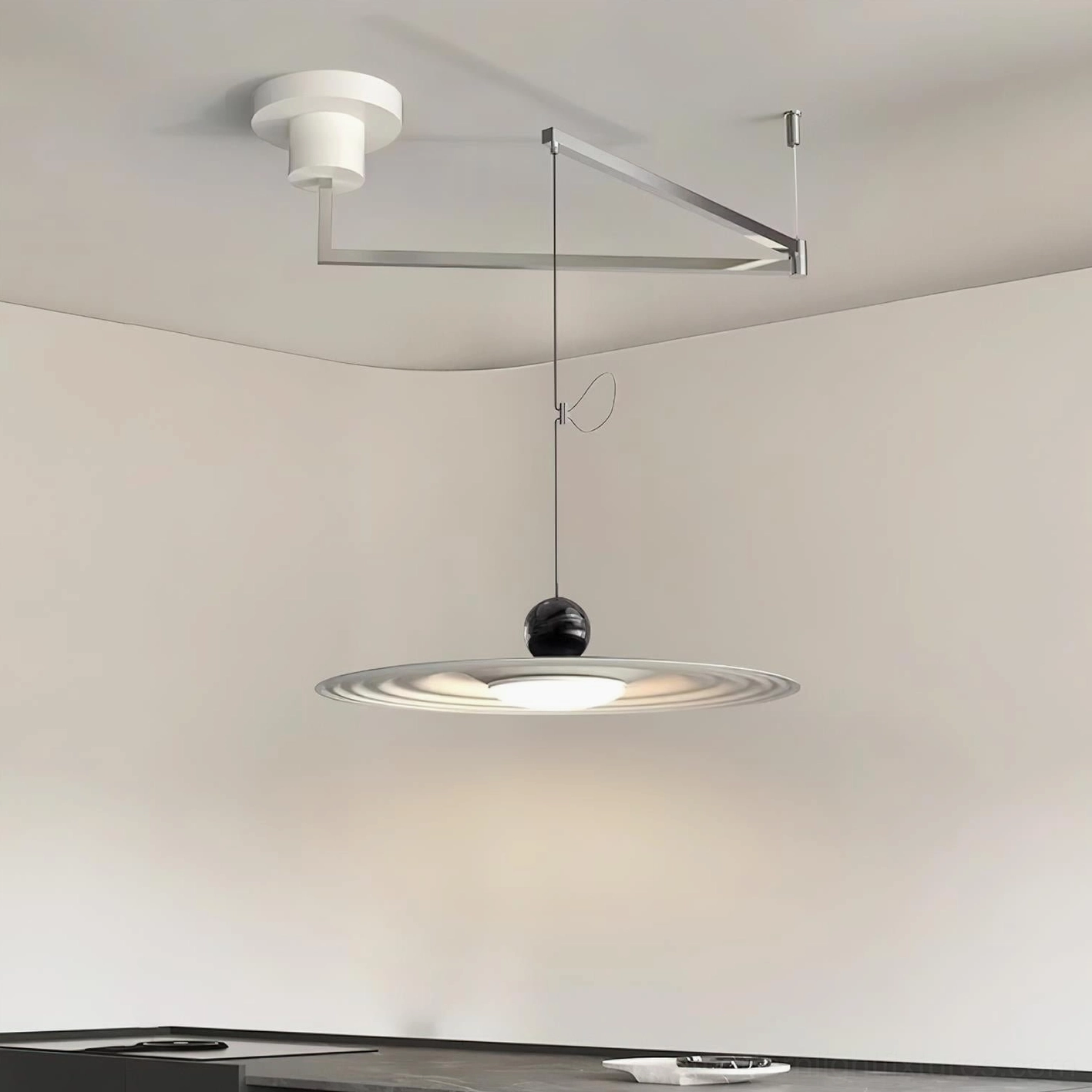 Adjustable swing arm pendant light with matte finish over dark kitchen countertop, modern minimalist design