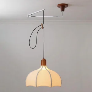 Side angle view of walnut and white swing arm pendant light showing adjustable cord and metal hardware