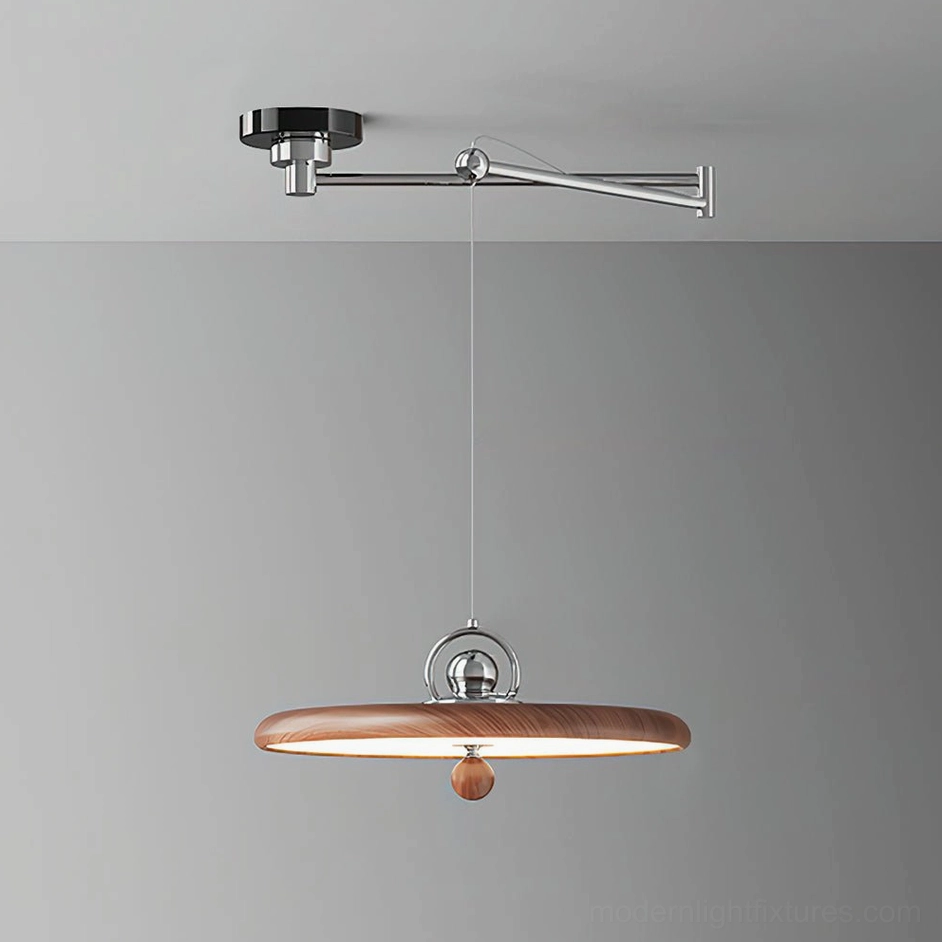 Walnut color swing arm pendant light displayed in studio with cream ceiling mount and warm amber decorative sphere accent