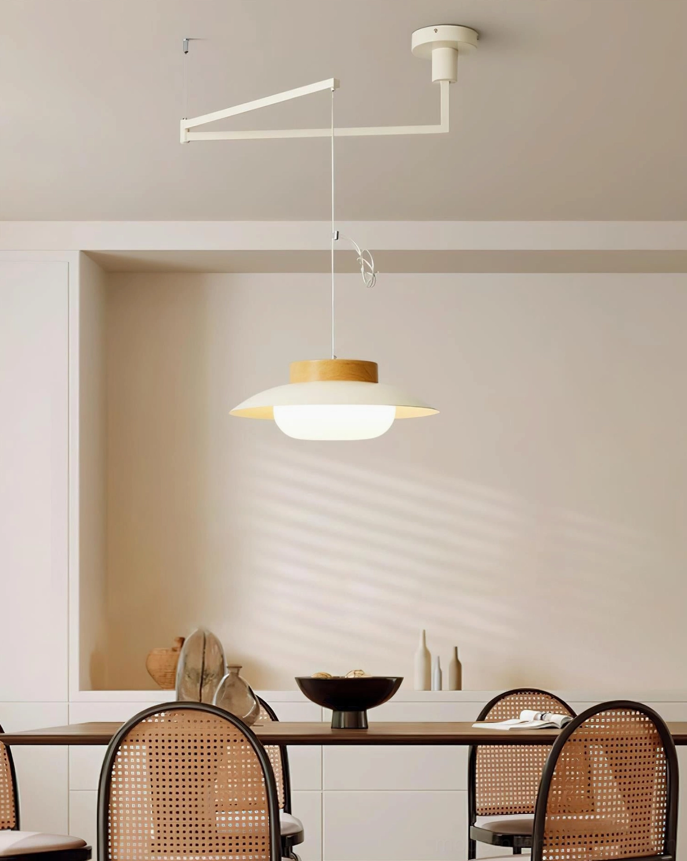 White swing arm pendant lamp suspended in modern home dining room with light yellow wood-tone shade