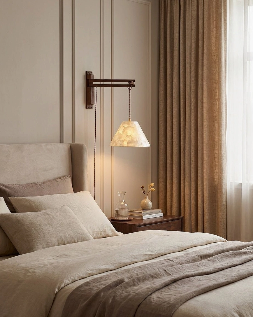 Bedside swing-arm wall sconce installed above nightstand in warm neutral bedroom, soft accent lighting
