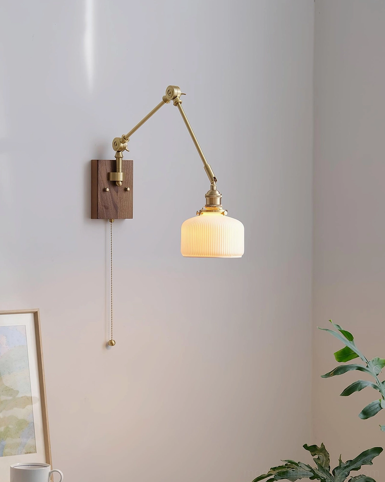 Wide ribbed ceramic shade swing arm wall sconce installed beside framed artwork, residential decor