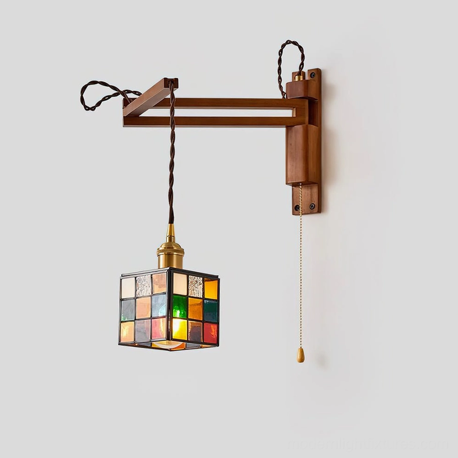 Vintage-style swing arm wall sconce with antique brass hardware and stained glass shade, three-quarter angle product view showing sculptural geometry