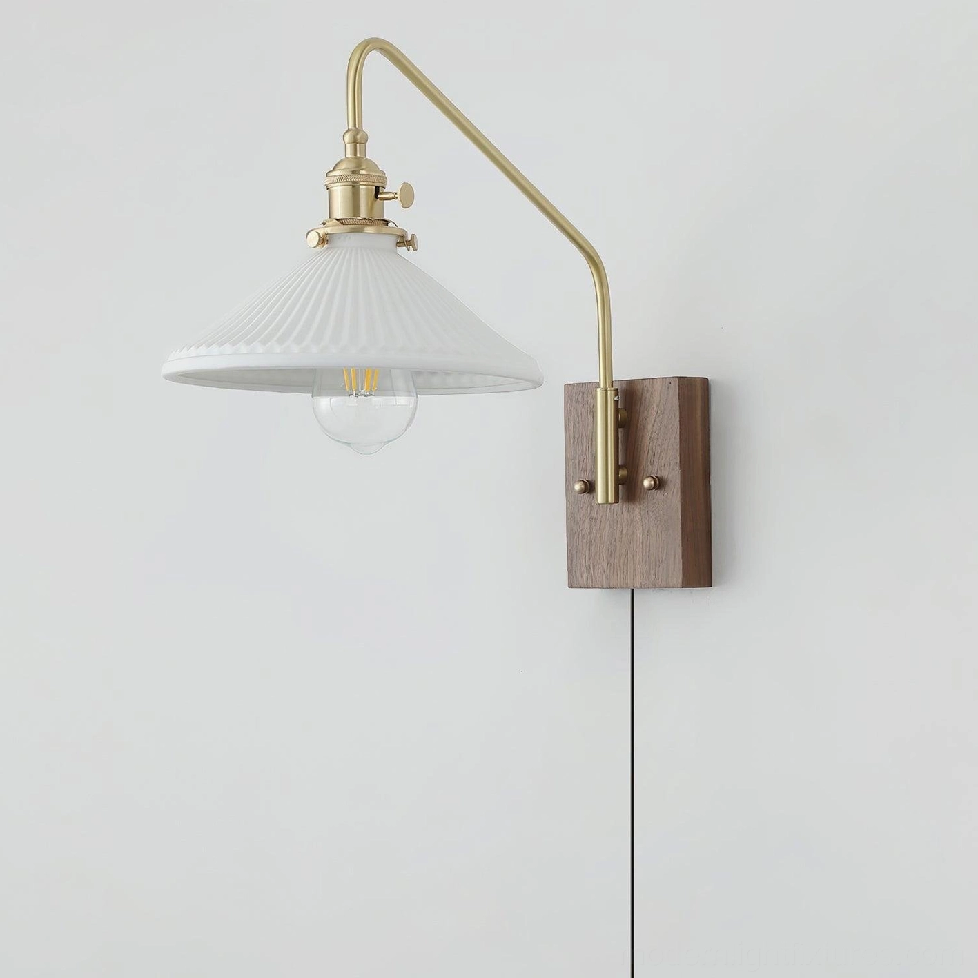 Adjustable swing arm wall sconce with exposed vintage bulb filament and rotating brass mechanism