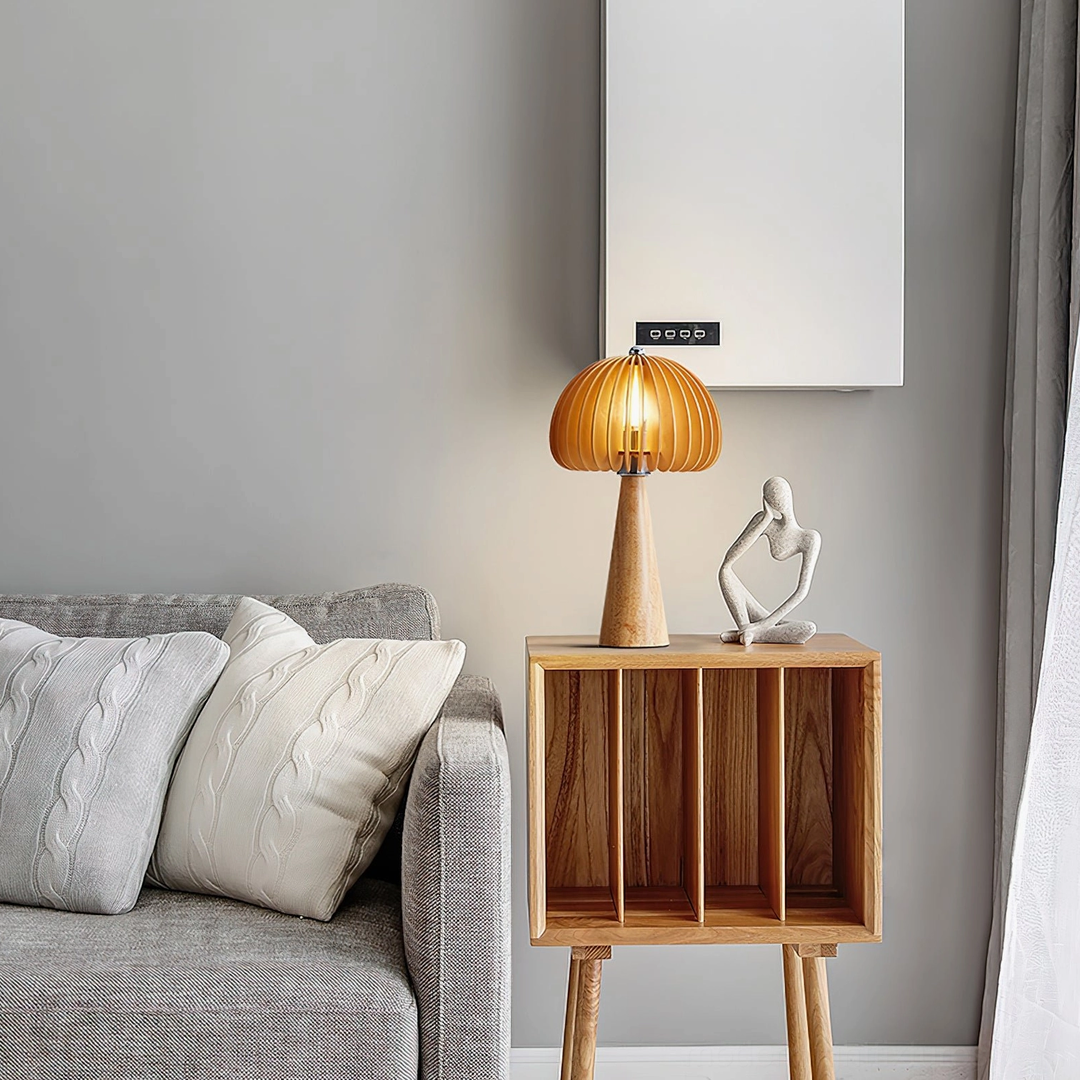 Sylora wooden table lamp on side table in modern living room with grey sofa, decorative sculpture, and warm ambient lighting