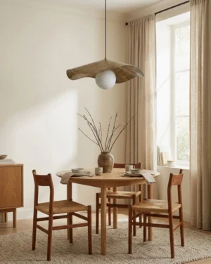 Sylvune pendant light hanging above dining table in modern dining room with natural wood furniture and bright window light