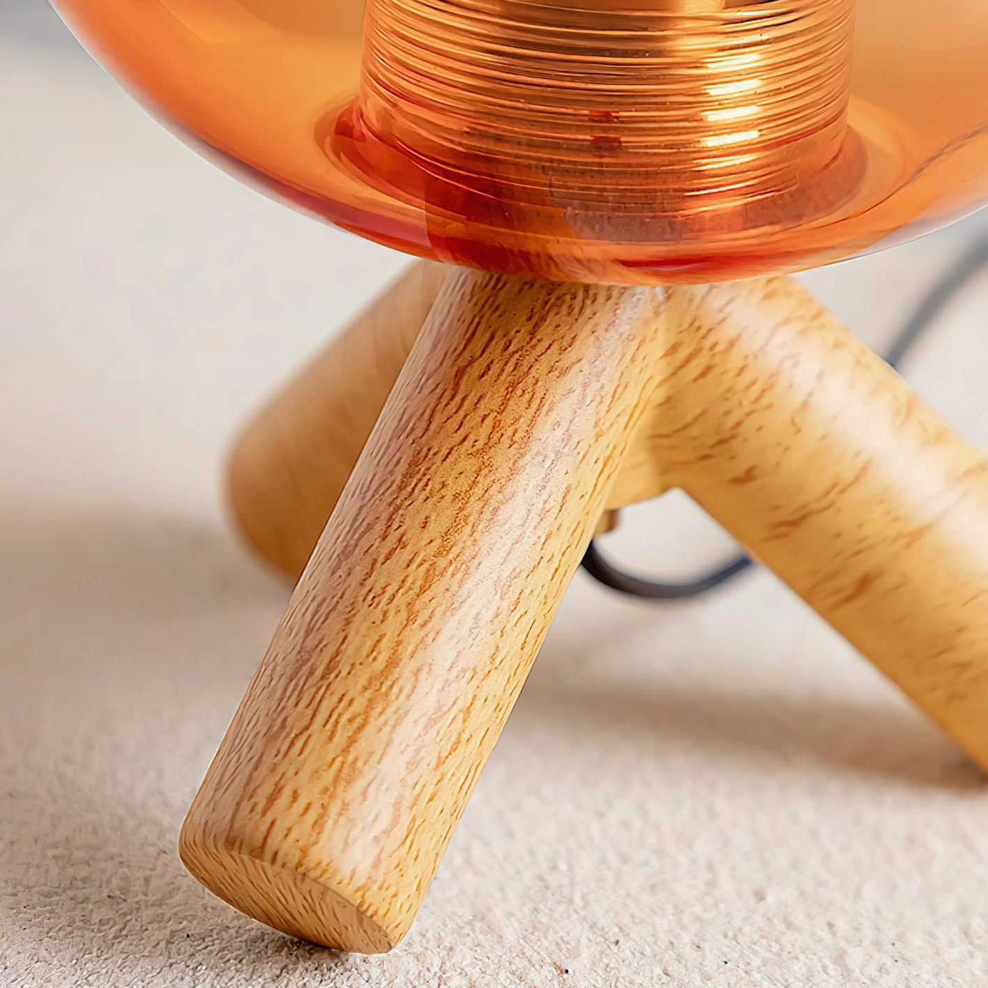 Close-up bottom view of lamp base joint showing wood grain texture, threaded metal connection, and amber glass underside detail