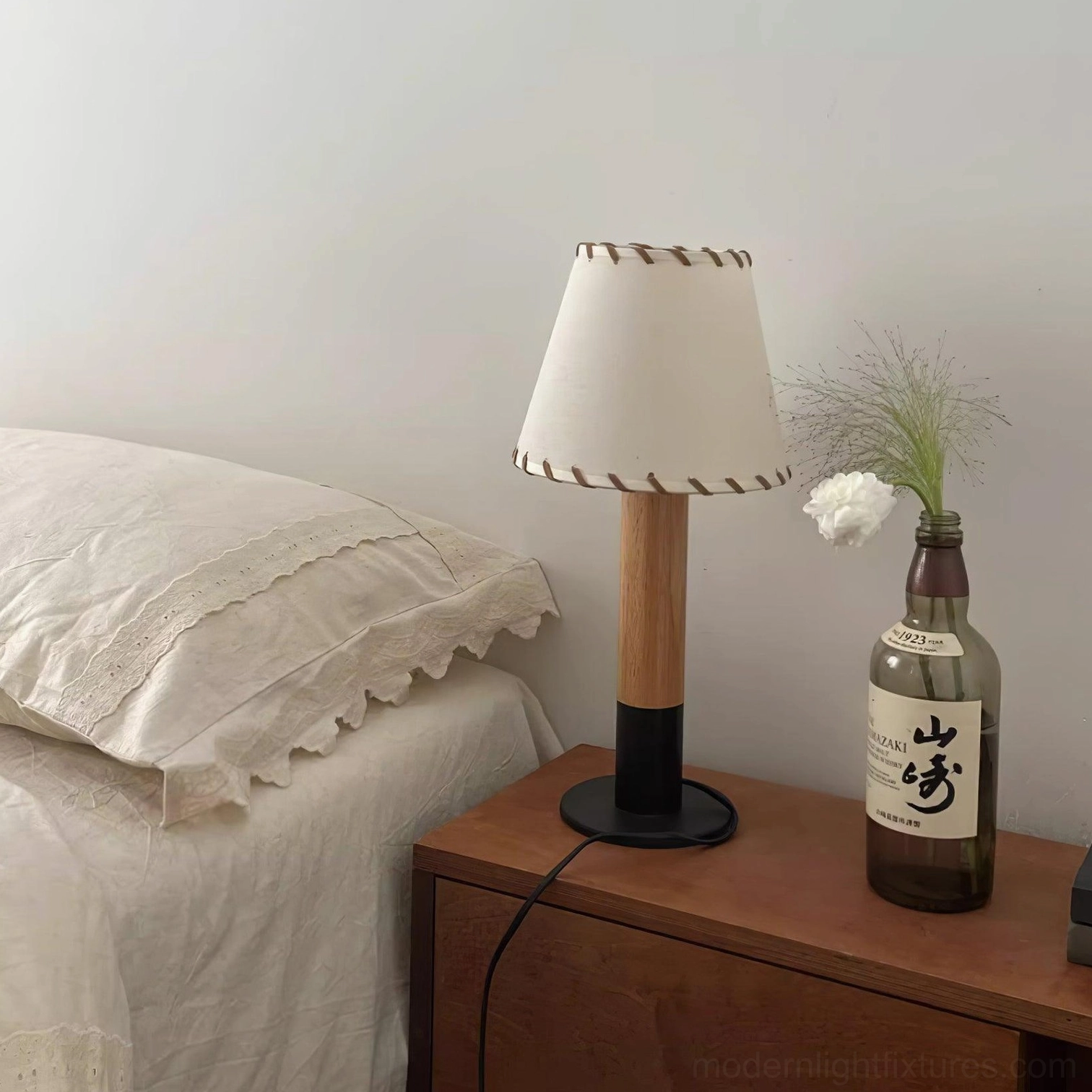 Rustic table lamp with hand-stitched fabric border detail on neutral interior setting