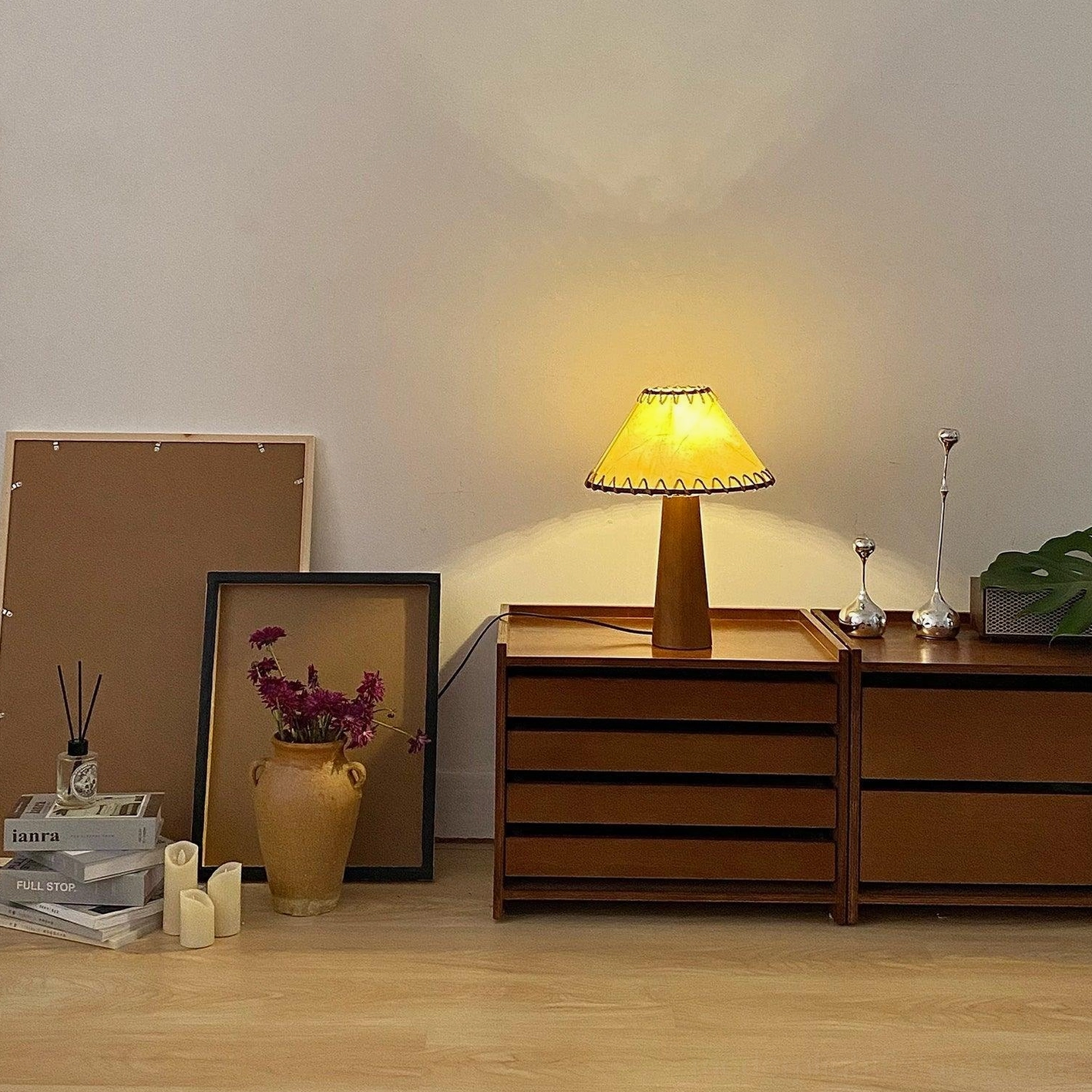 Table lamp with natural wood construction and jute shade in living room side table arrangement with accessories
