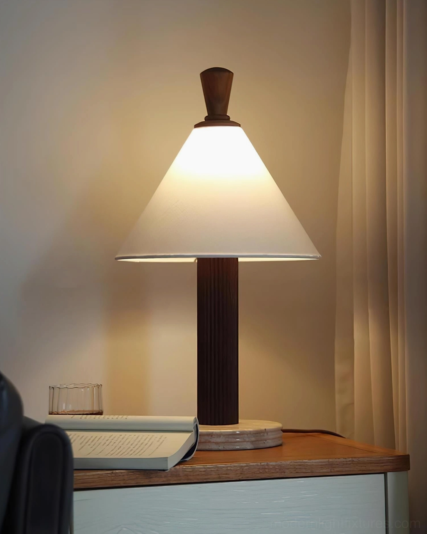 Lit Takumi table lamp in living room sofa corner with dark fluted wood pole and cozy lounge lighting