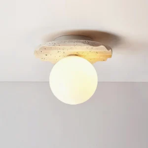 Illuminated Talia modern flush mount ceiling lamp with wavy travertine base and frosted glass shade, close-up frontal view