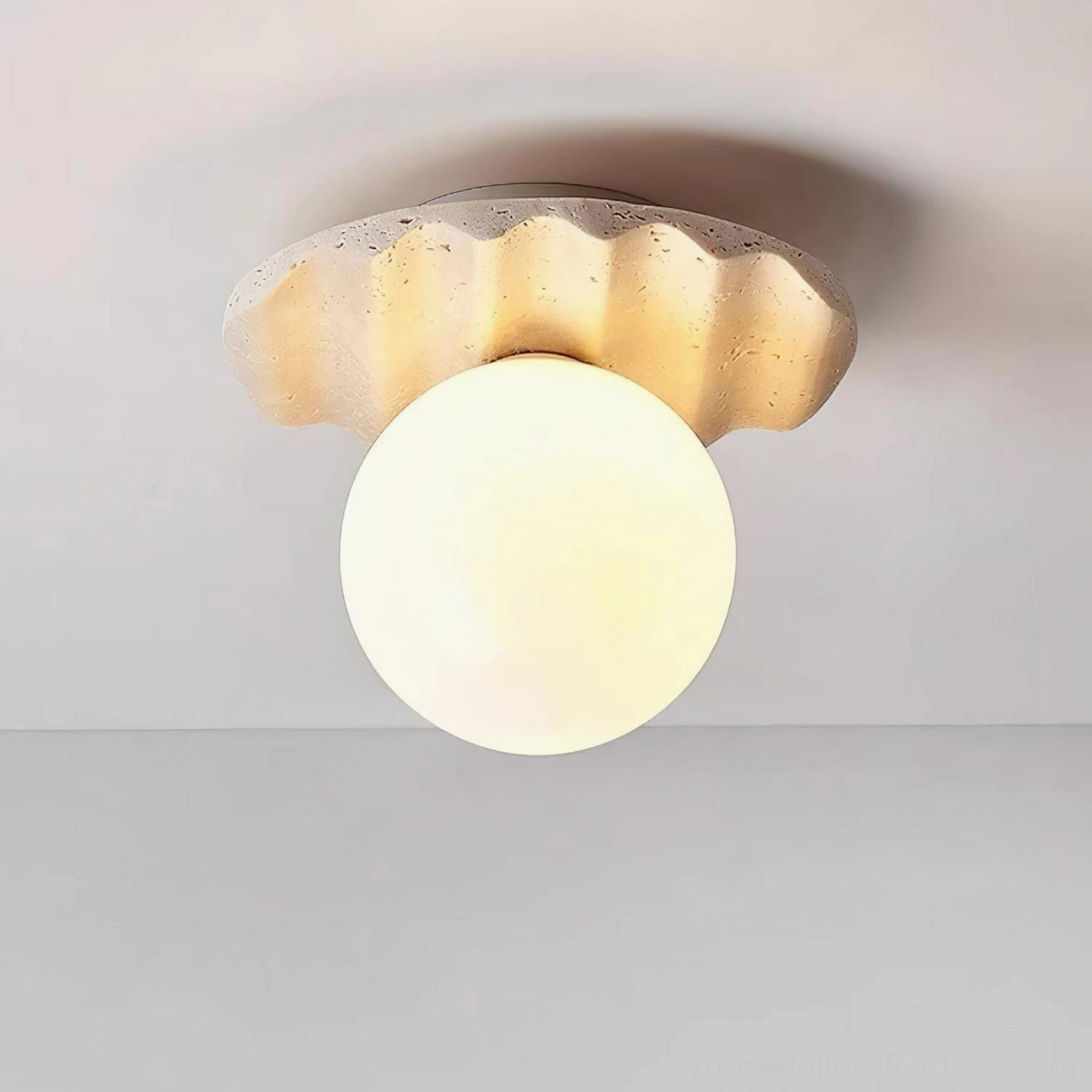 Talia modern flush mount ceiling light with warm glowing frosted glass shade and textured organic travertine base