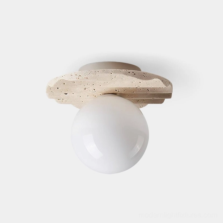 Talia travertine ceiling light fixture with frosted glass sphere diffuser, top-down close-up view showing textured stone base and glowing warm light