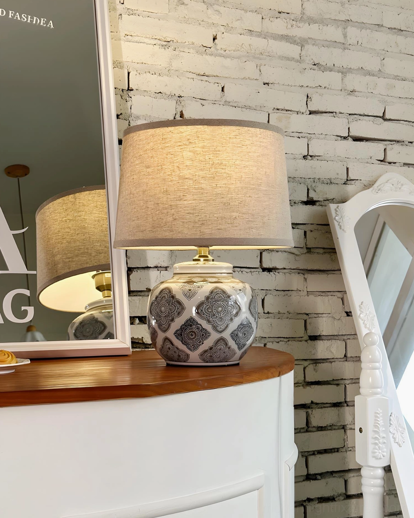 Contemporary ceramic table lamp against brick wall with full-length mirror and vanity setup