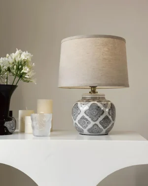 Modern ceramic table lamp with black and white patterned base styled on console table with floral and candle decor