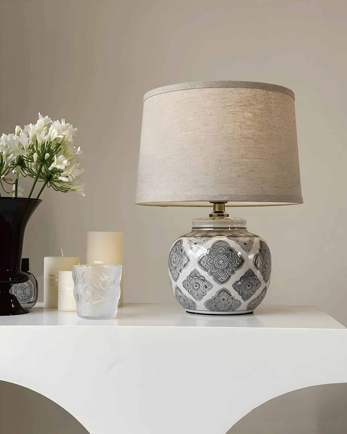 Modern ceramic table lamp with black and white patterned base styled on console table with floral and candle decor