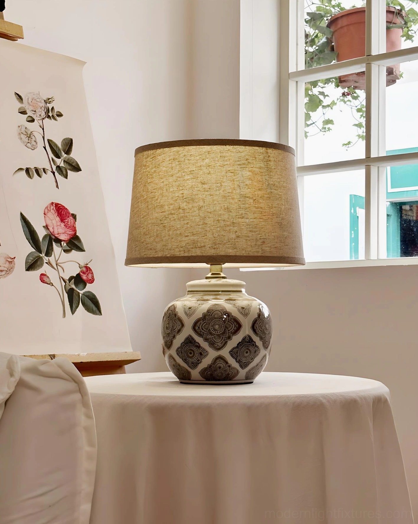 Talora ceramic drum lamp on round side table by window with geometric patterned base and beige fabric shade
