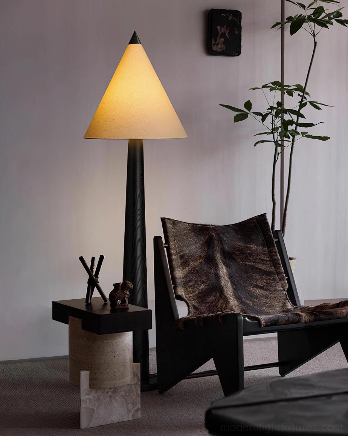 Mid-century modern tapered floor lamp with black pole and beige shade next to leather lounge chair