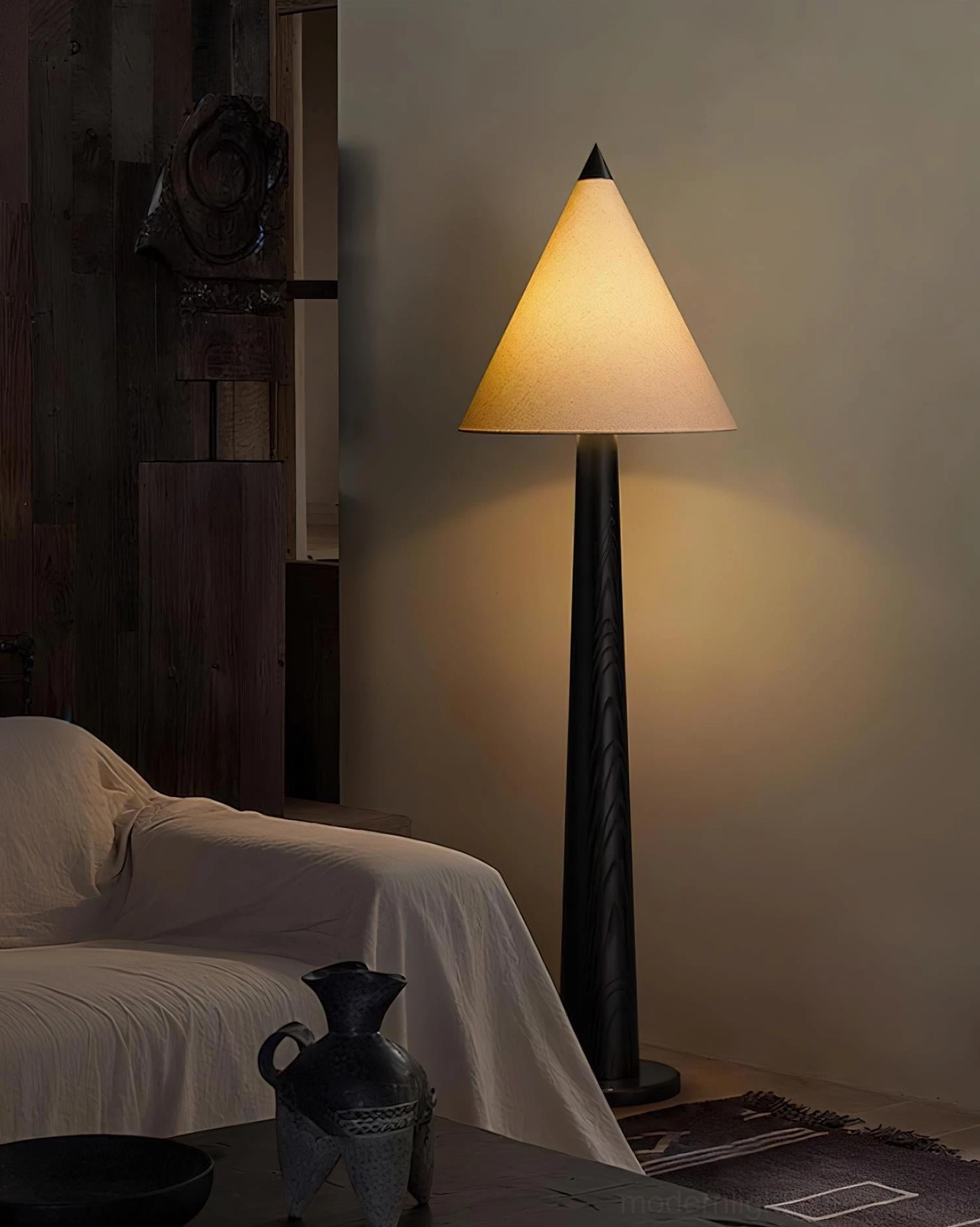 Vintage-style tapered floor lamp with black pole and warm beige linen shade in dark rustic lounge