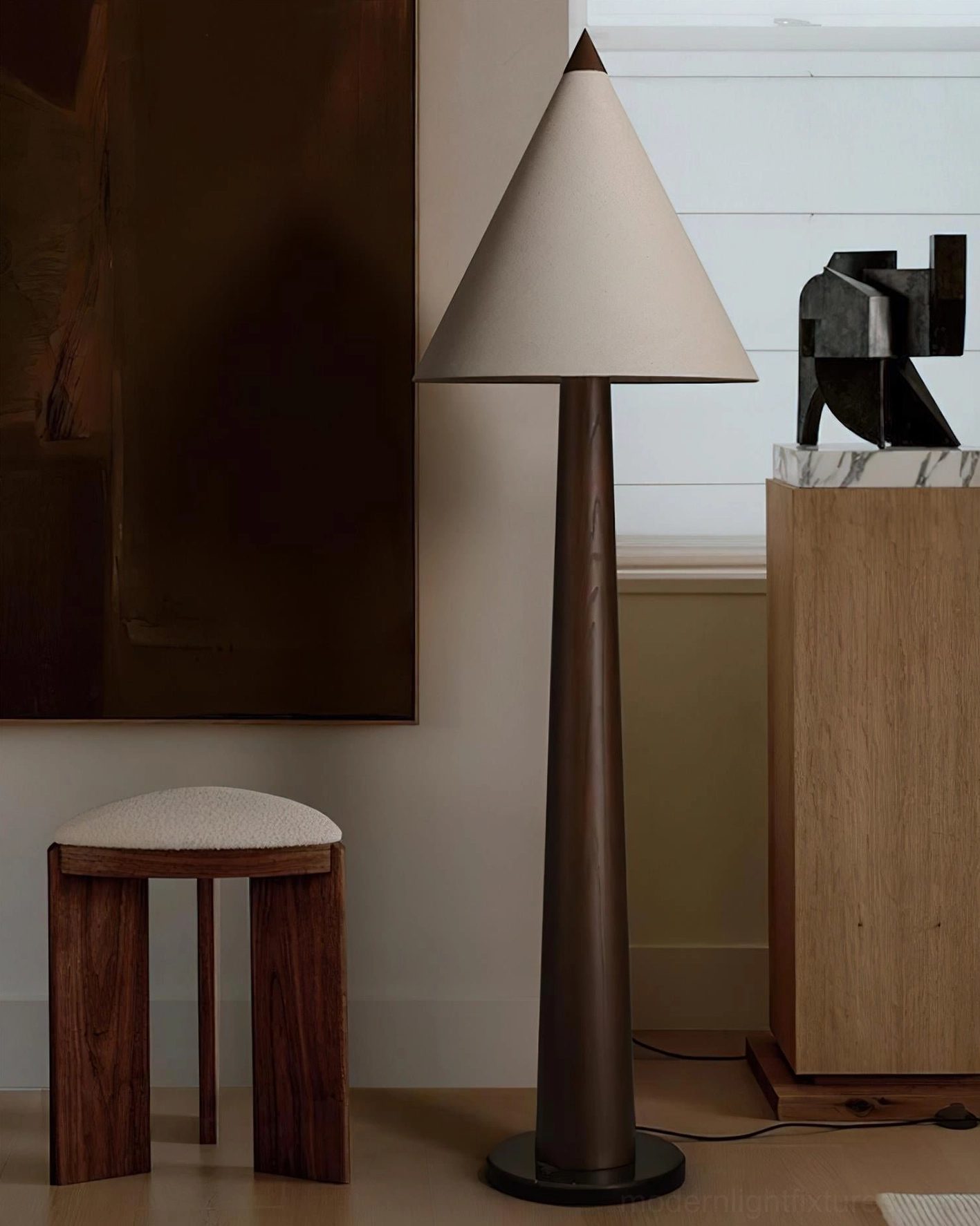 Wabi-sabi minimalist floor lamp with off-white linen shade and dark brown tapered pole next to wooden stool