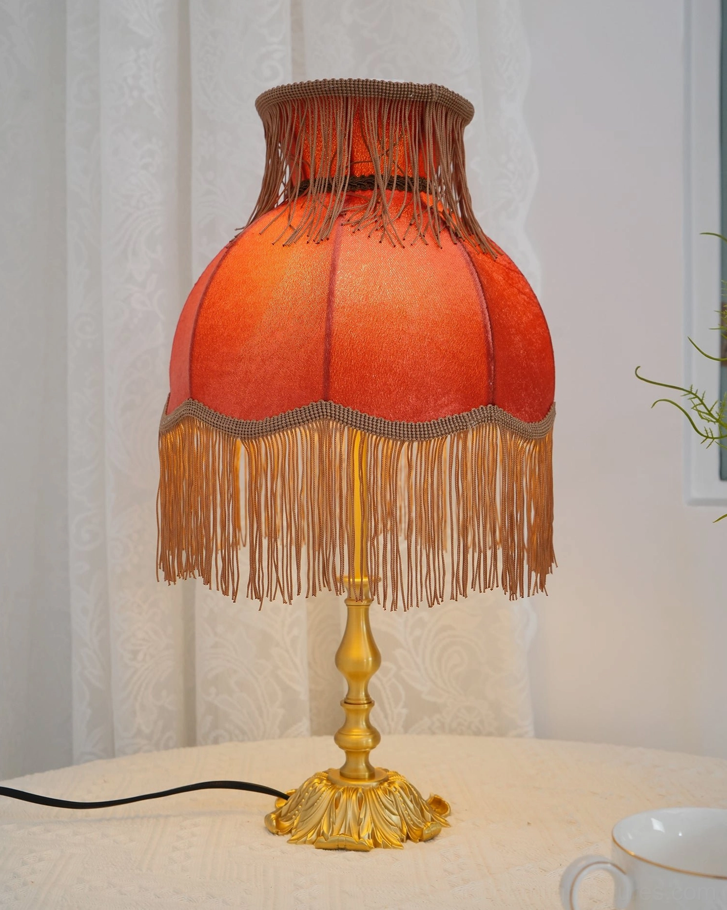Handmade tassel table lamp with burnt orange fringe shade and ornate brass base front lighting