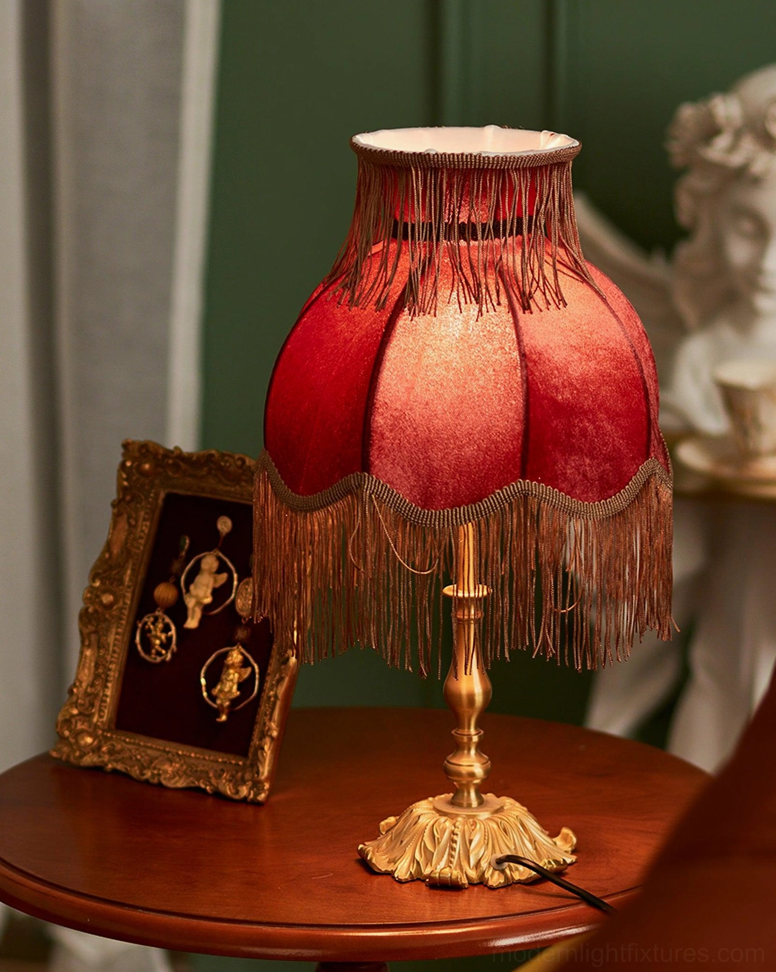 Decorative tassel table lamp with red velvet fringe shade and carved brass base side view