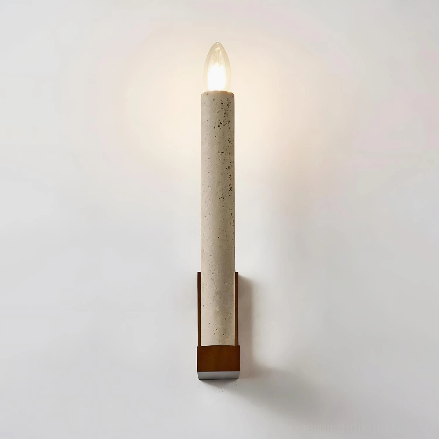 Tavero wall sconce illuminated at dusk creating ambient glow with natural stone and wood materials