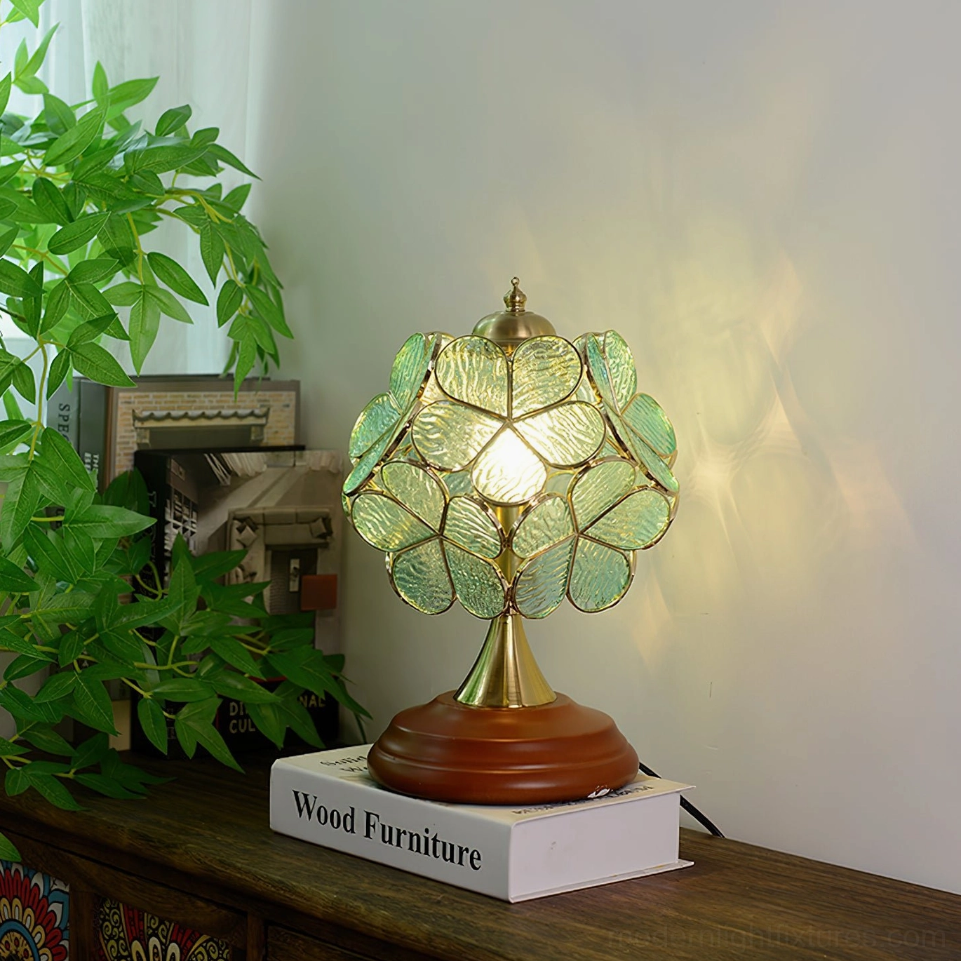 Green blue stained glass Tiffany table lamp with flower petal design illuminated in home setting