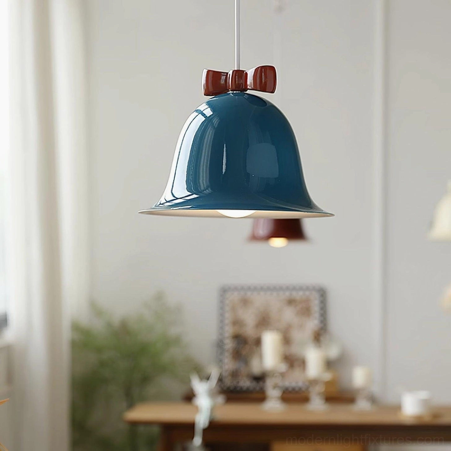 Navy teal ceramic bell pendant light with matching bow accent hanging above dining table ornaments