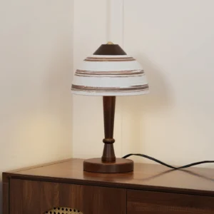 Tera mid-century modern table lamp three-quarter view in interior setting with illuminated ceramic accents and dark wood base