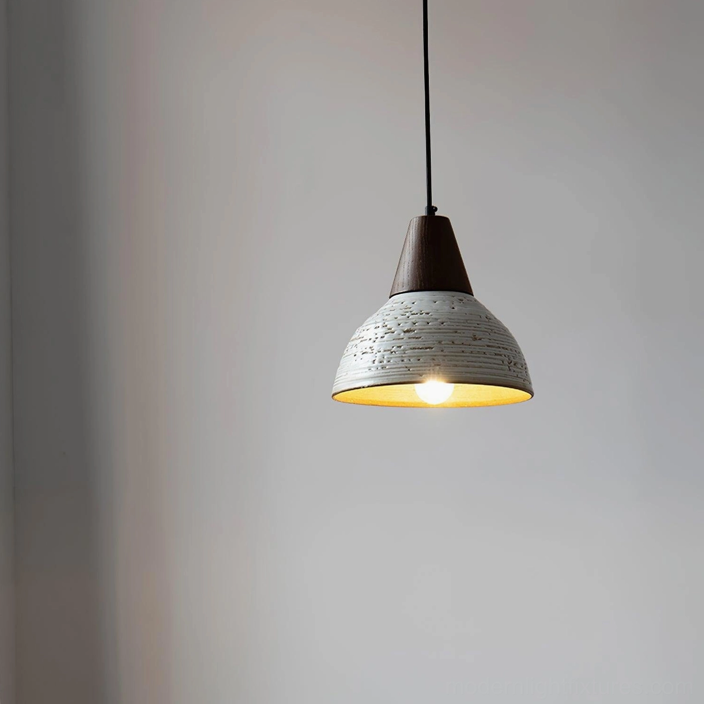 Tera ceramic pendant lamp illuminated with warm glowing bulb, side angle view highlighting diffused ambient light and textured shade