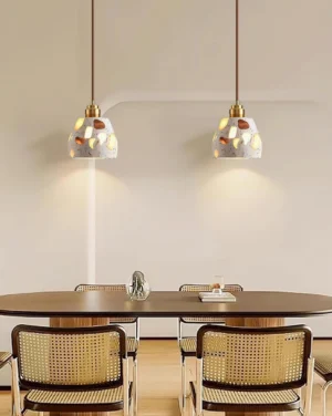Pair of terrazzo pendant lights suspended above round dining table in minimalist dining room with warm ambient glow