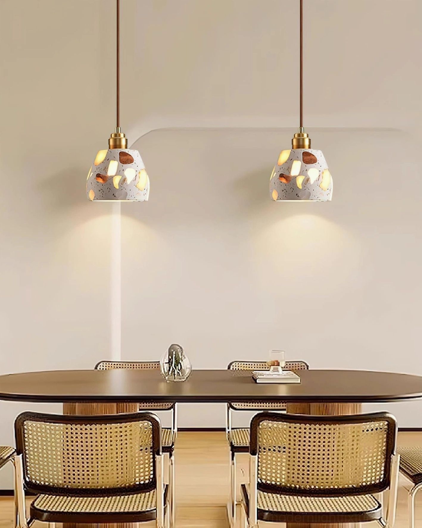 Pair of terrazzo pendant lights suspended above round dining table in minimalist dining room with warm ambient glow
