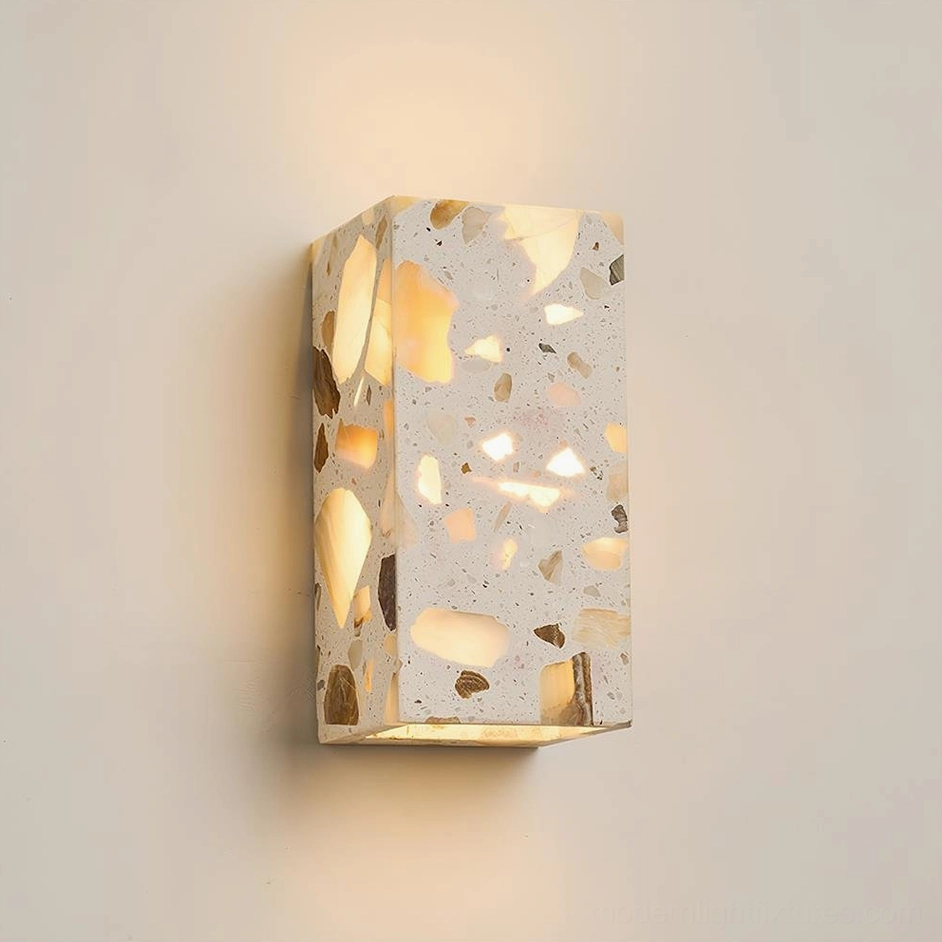 Vertical rectangle terrazzo wall sconce 8cm x 16cm in grey casting warm ambient light with three-quarter perspective showing aggregate texture detail