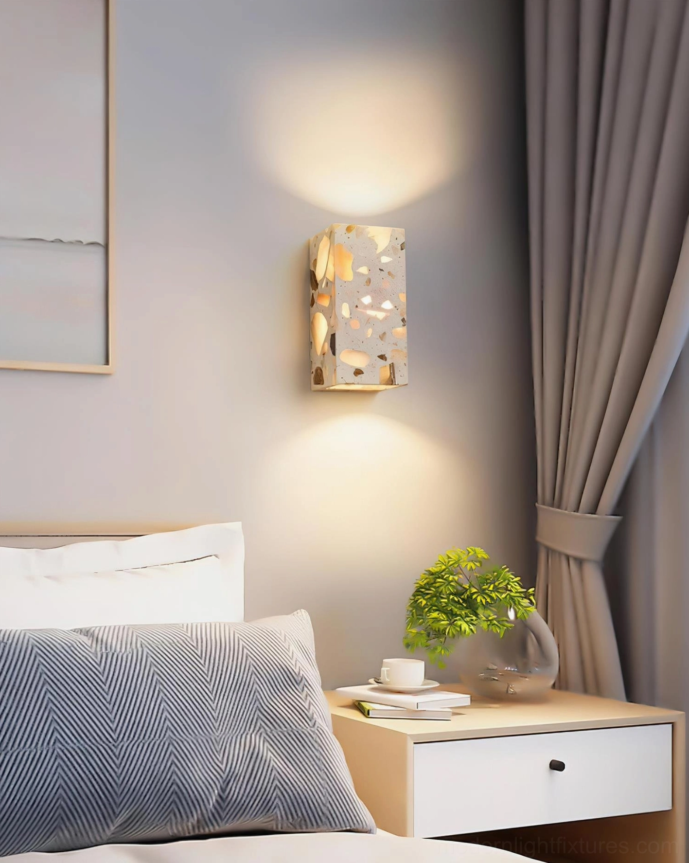 Terrazzo wall sconce mounted in bedroom three-quarter view showing warm glow against wall with subtle illumination and natural stone texture