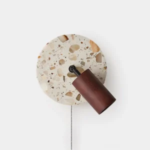 Terrazzo wall sconce with wooden spotlight head and amber pull-chain detail, front view on white wall