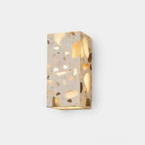 Terrazzo wall sconce front view with warm glowing integrated LED light casting dappled illumination from embedded natural stone fragments