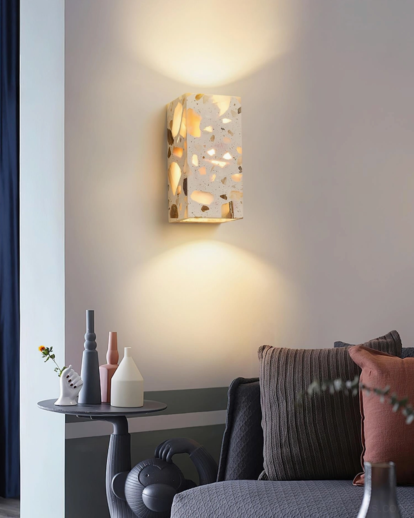Terrazzo wall sconce in contemporary living room creating warm dappled light accent above sofa with minimalist modern decor styling