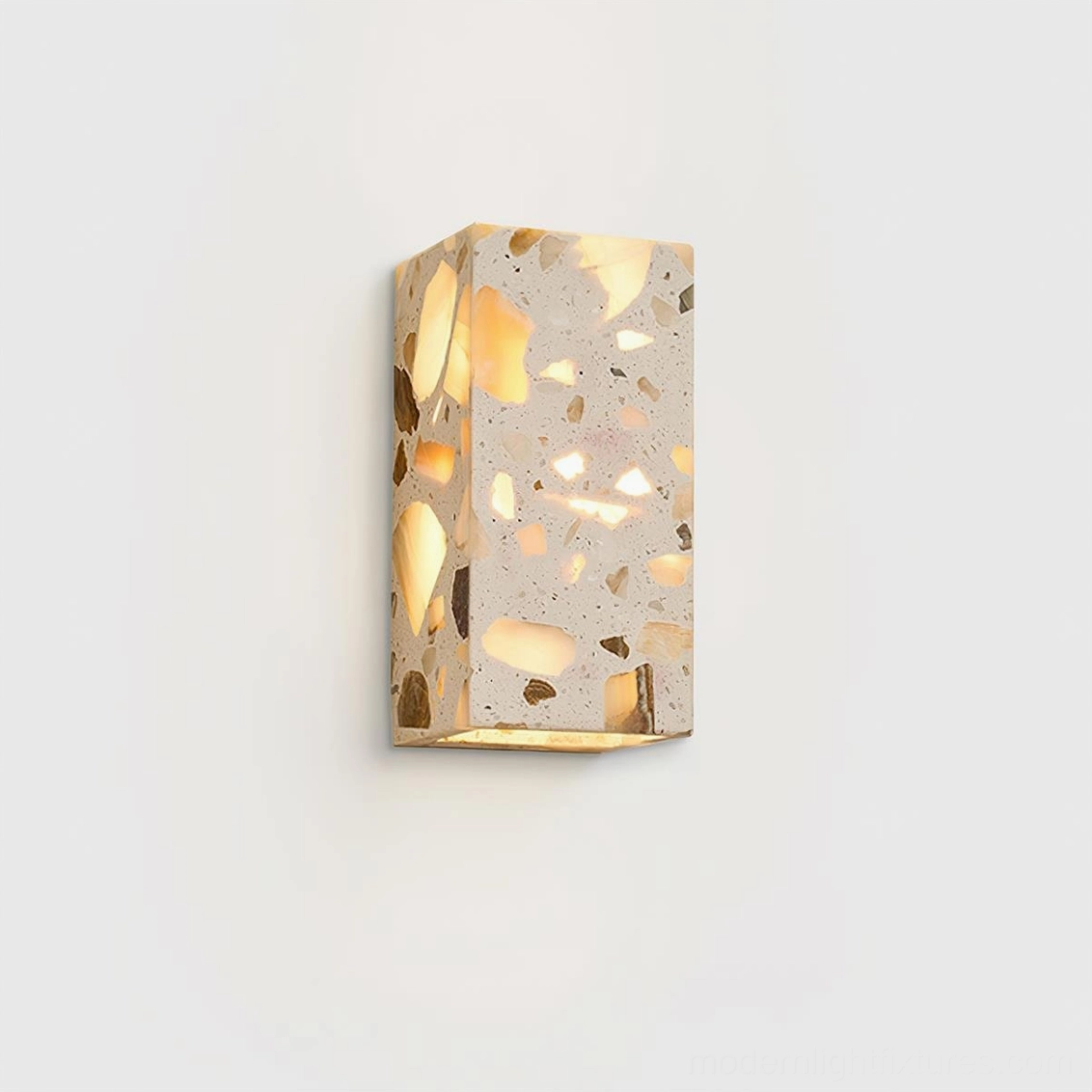 Terrazzo wall sconce close-up front view on white background highlighting translucent natural stone chip inlays glowing warm white LED light