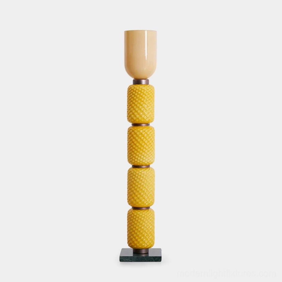 Tessara geometric floor lamp with honey-toned stacked diamond-patterned glass column and cylindrical shade on marble base, frontal studio view