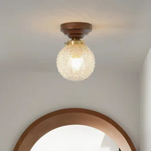 Vintage modern flush mount ceiling light installed in residential hallway, warm glowing glass globe with dark wood base