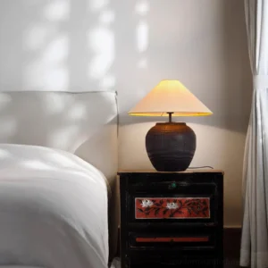 Modern resin table lamp with fabric shade on vintage bedside nightstand in bedroom