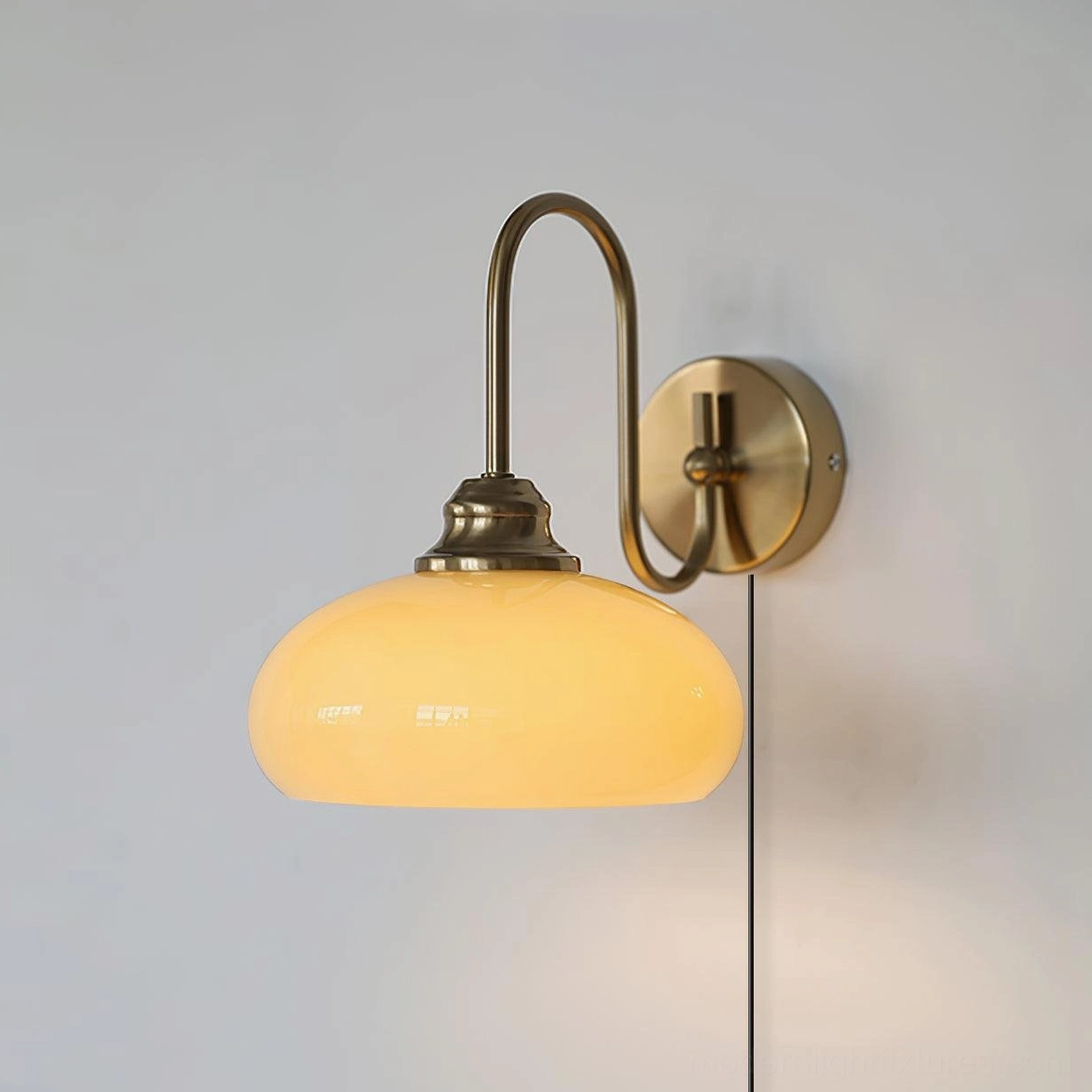 Textured glass plug-in sconce in gold brass finish with warm milk glass shade, bedroom bedside installation above pillow area