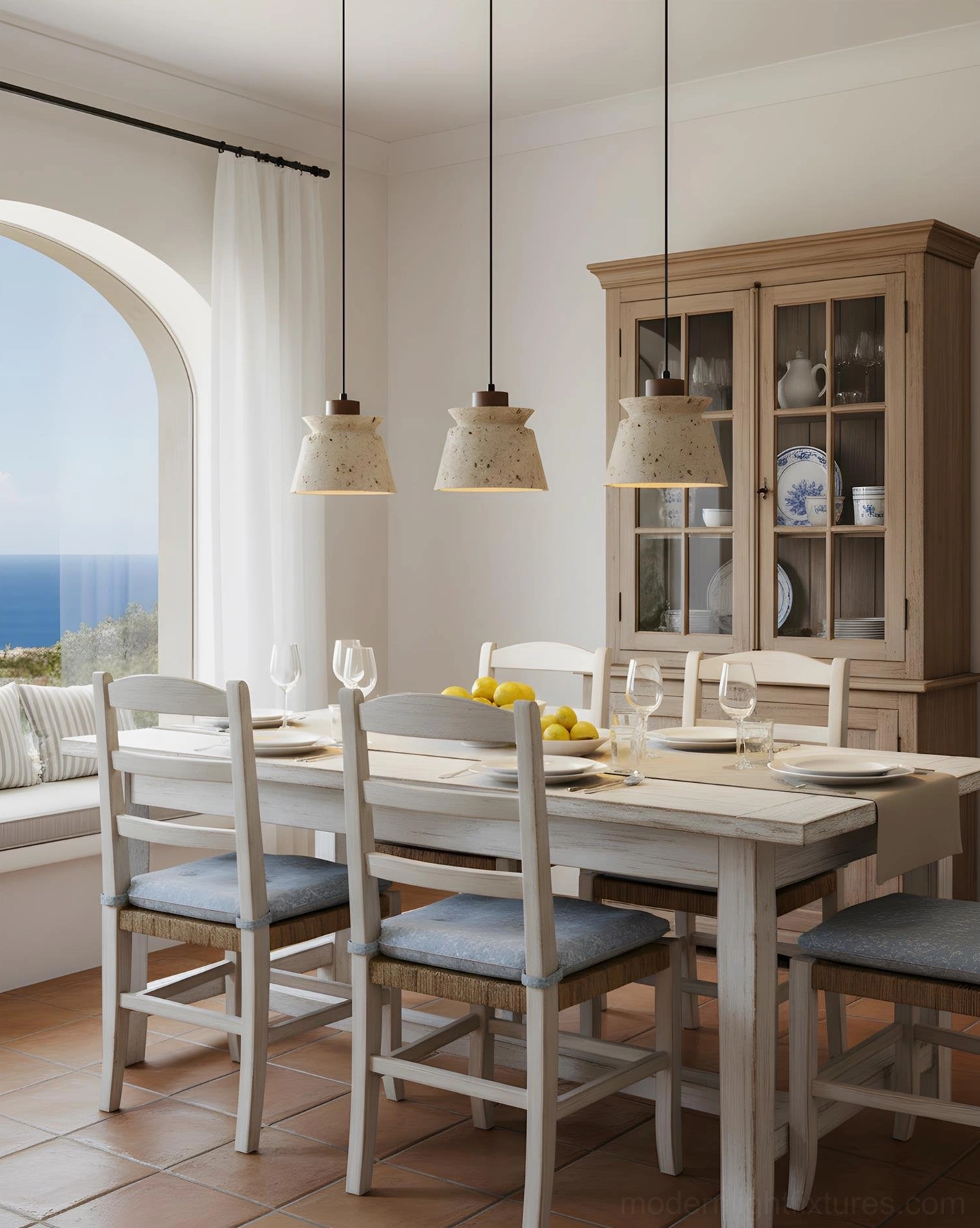 Farmhouse coastal dining room featuring three travertine pendant lights suspended over white wooden dining set with ocean view